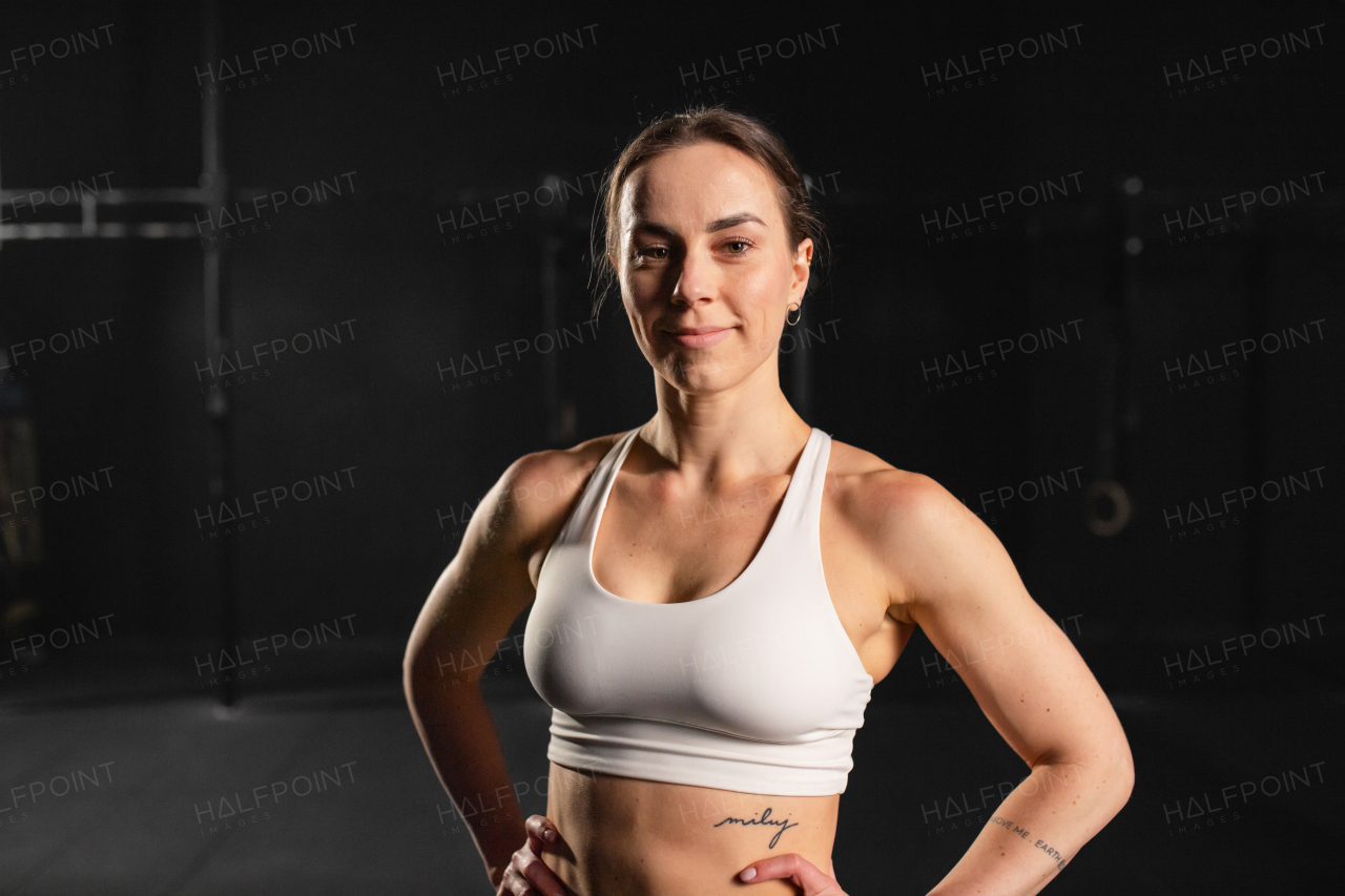 Portrait of young muscular woman in gym, wearing sportswear. Routine workout for physical and mental health.