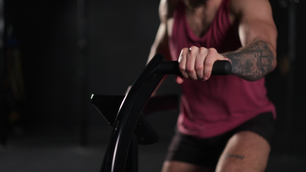 Close up of a man exercising on elliptical cross-trainer machine, wearing an activewear. Routine workout for physical and mental health.