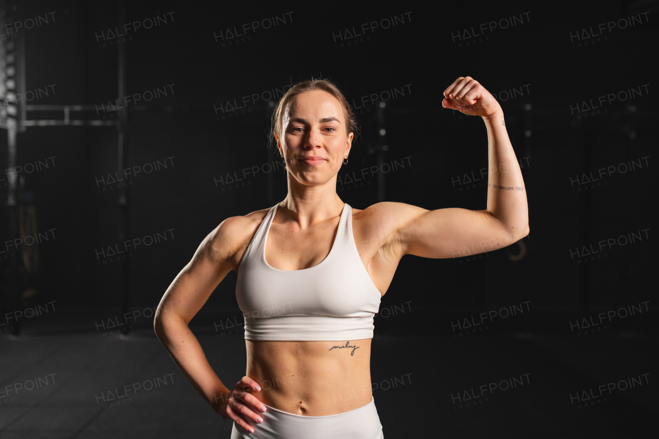 Portrait of young muscular woman in gym, wearing sportswear. Routine workout for physical and mental health.