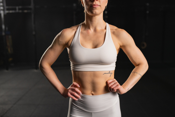 Front view of young muscular woman in gym, wearing sportswear. Routine workout for physical and mental health.