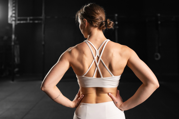 Rear view of young muscular woman in gym, wearing sportswear. Routine workout for physical and mental health.