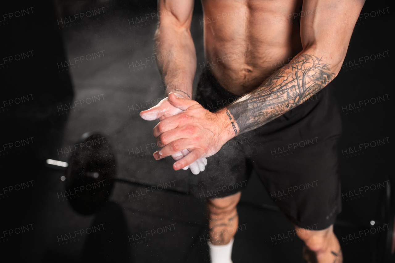 Beautiful sport woman preparing for exercise, using chalk on her hands. Routine workout for physical and mental health.