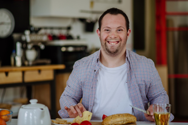 Independent man with down syndrome preparing a brekfast in his apartment.