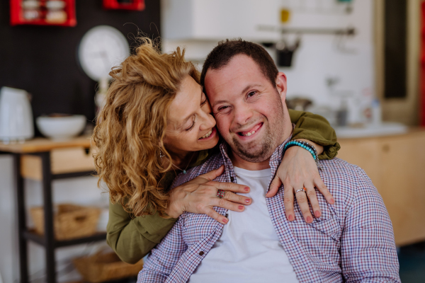 A portrait of mother hugging her grown up son with Down syndrome, motherhood concept.