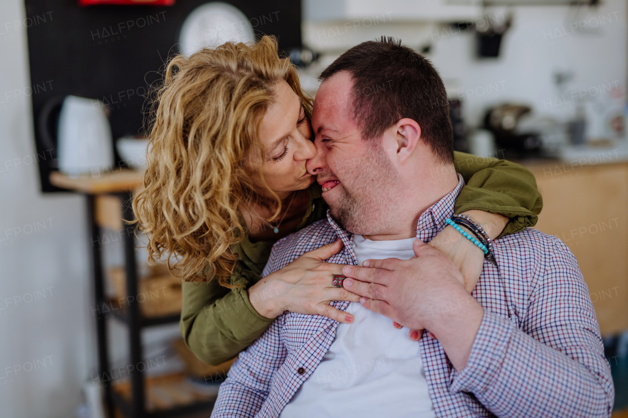 A portrait of mother hugging her grown up son with Down syndrome, motherhood concept.