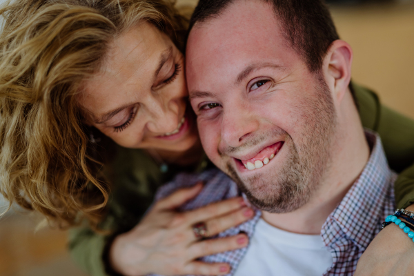 A portrait of mother hugging her grown up son with Down syndrome, motherhood concept.