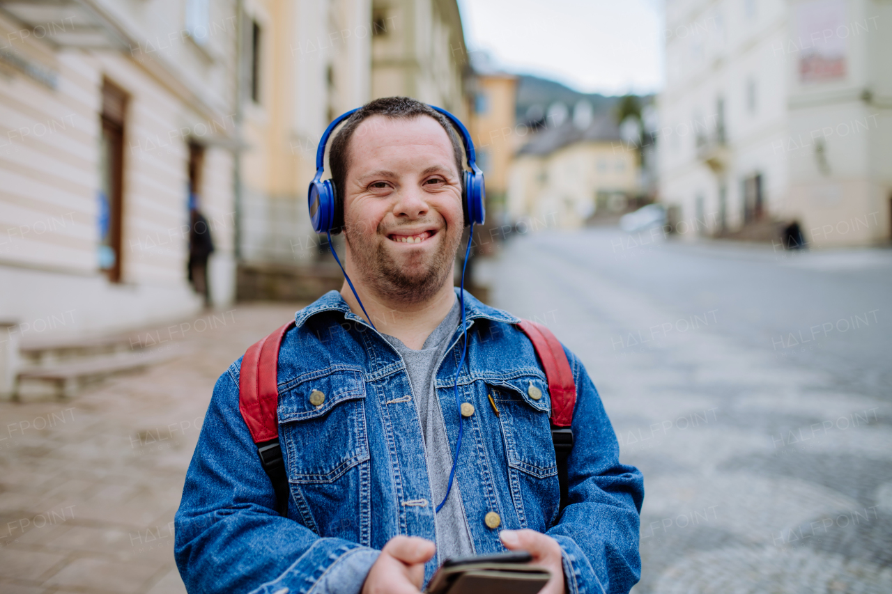 A happy young man with Down sydrome listening to music when walking in street.