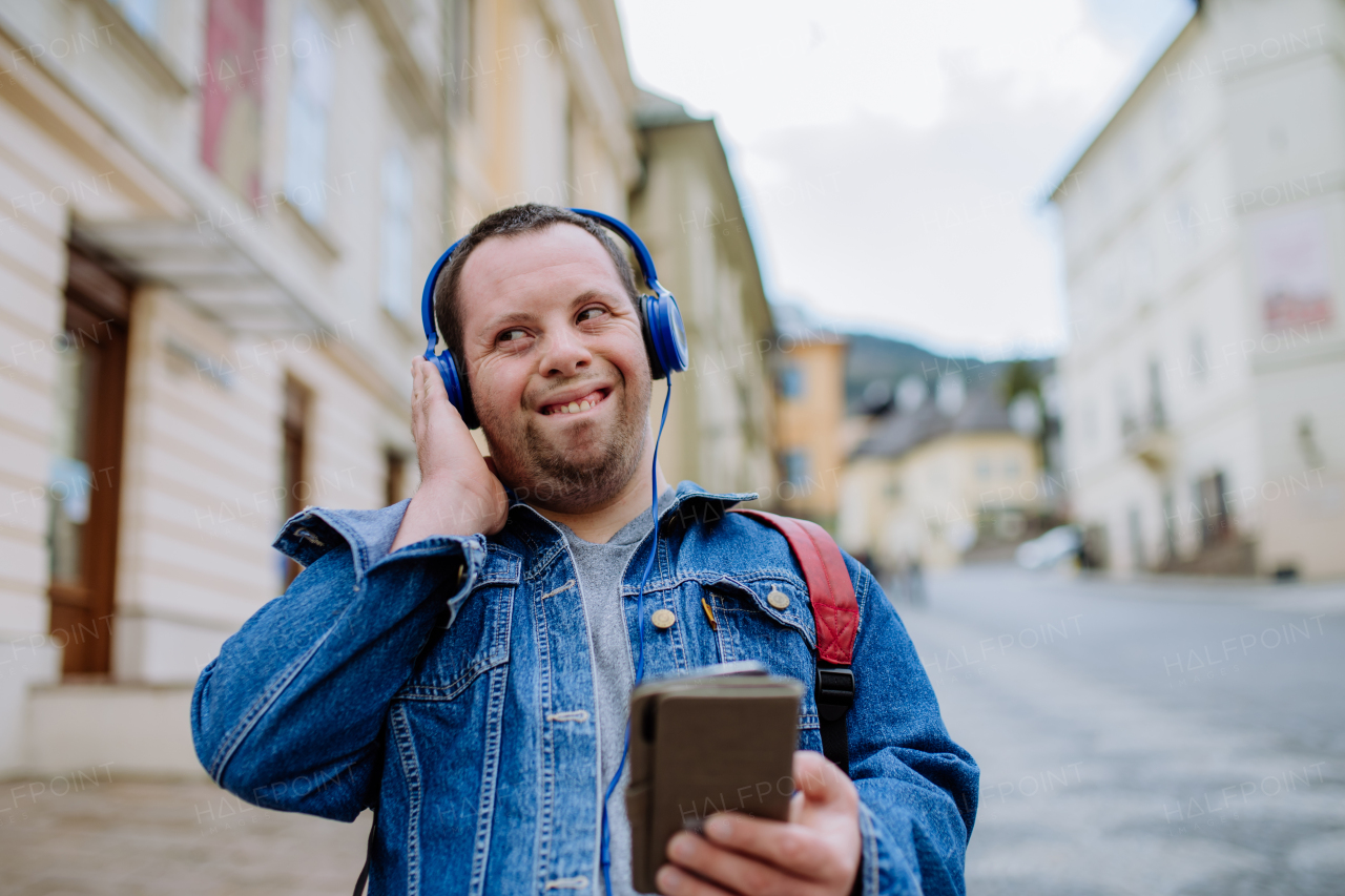 A happy young man with Down sydrome listening to music when walking in street.