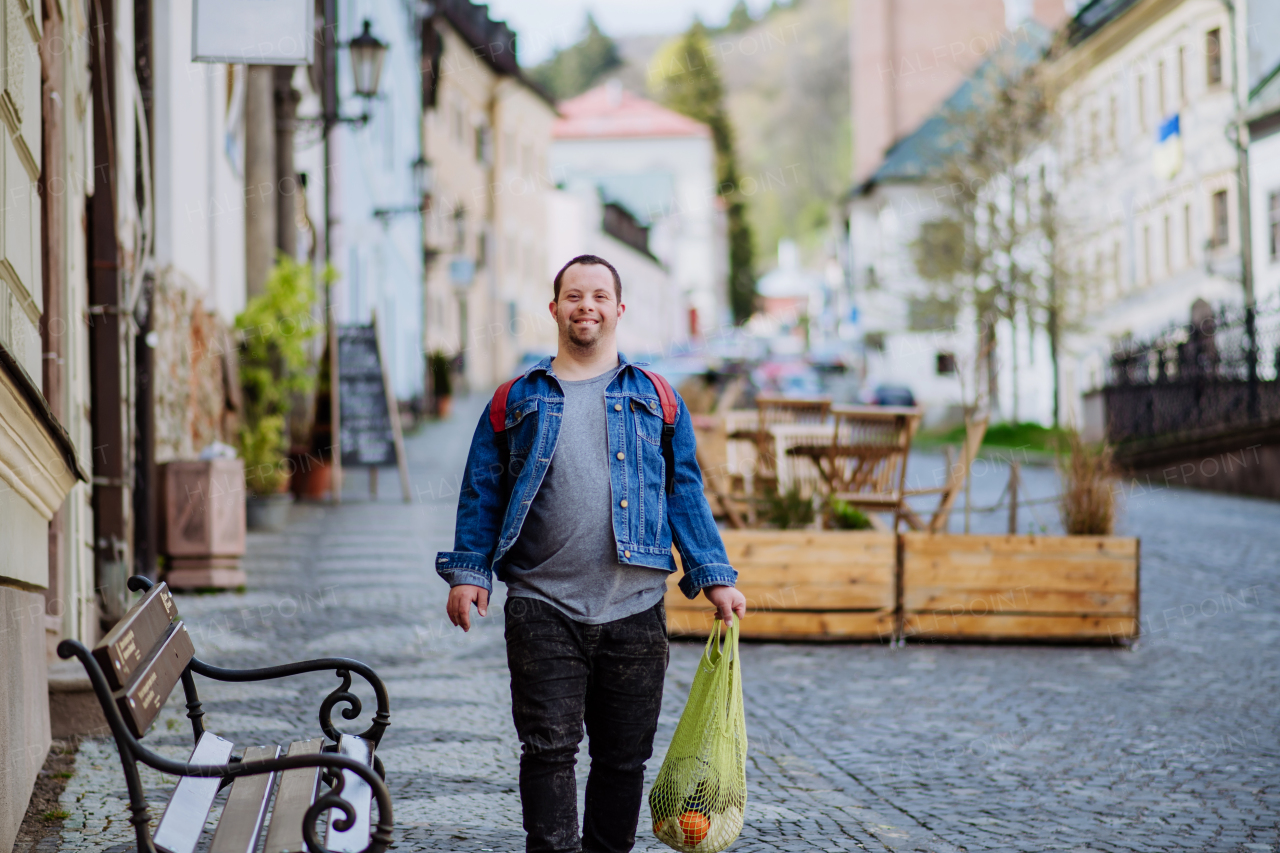 An independent young man with Down syndrome going back from gocery store with purchase.