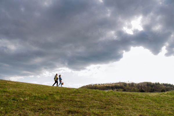 A happy young man with Down syndrome with his mother walking together in nature.