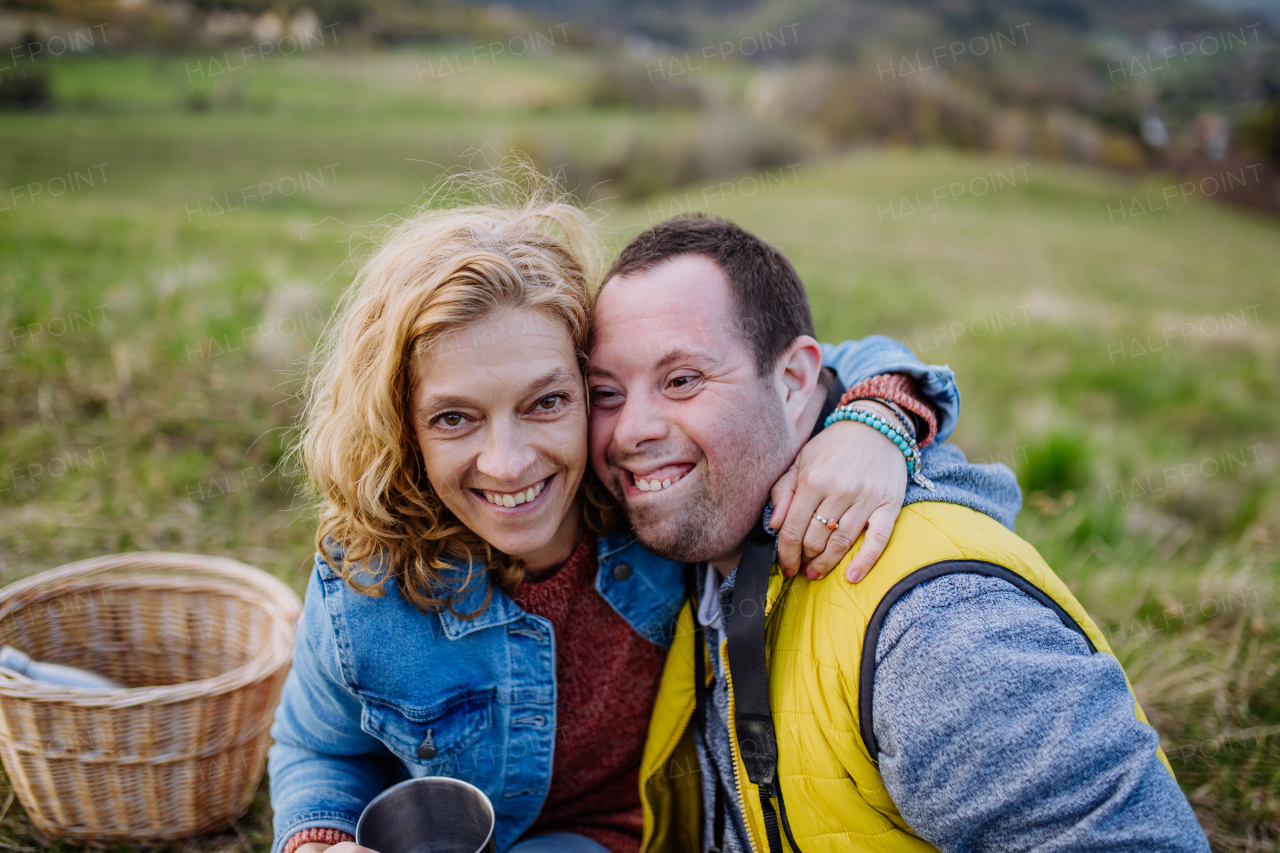 An outdoor portrait of mother hugging her grown up son with Down syndrome, motherhood concept.