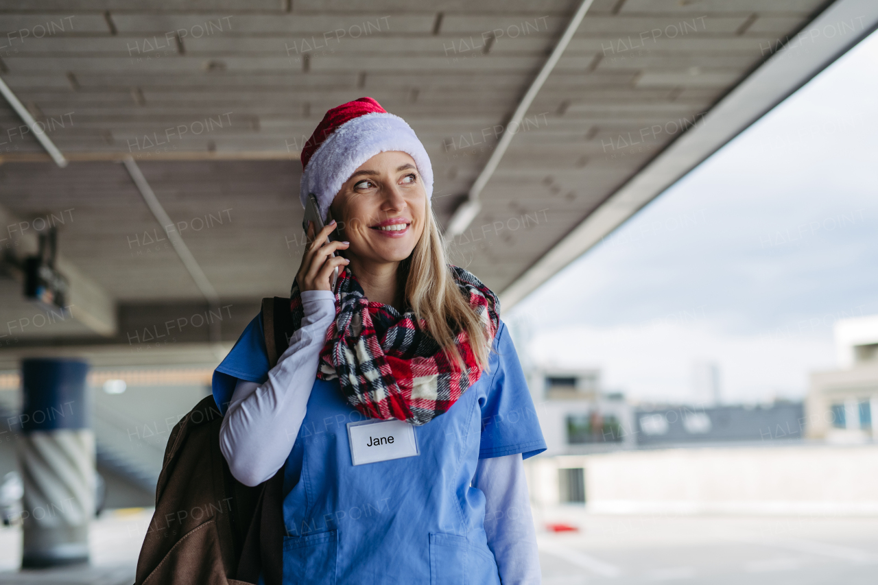 Portrait of beautiful nurse with christmas hat making call. Working in hospital on the Christmas day, Christmas Eve. Female doctor working a Christmas shift and can't be with her family.