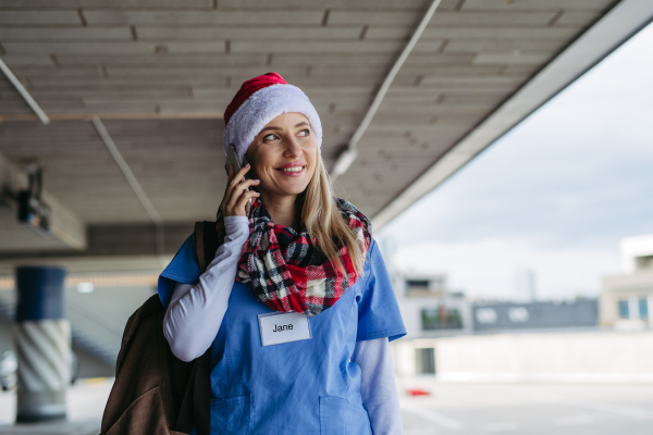 Portrait of beautiful nurse with christmas hat making call. Working in hospital on the Christmas day, Christmas Eve. Female doctor working a Christmas shift and can't be with her family.