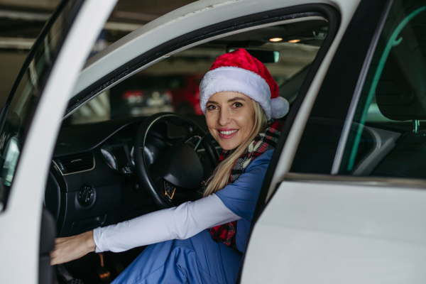 Beautiful nurse with christmas hat finishing a shift at the hospital and going home. Working in hospital on Christmas day or Christmas Eve. Female doctor arriving at Christmas shift and can't be with her family.