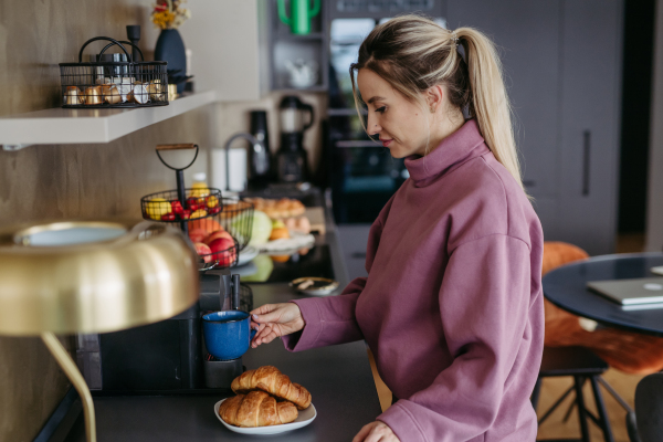 Female nurse, doctor getting ready for work, making breakfast and coffee on coffee maker. Work-life balance for healthcare worker.