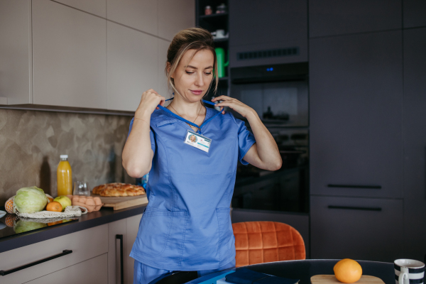 Female nurse getting home from work. taking off her ID tag from around neck. Work-life balance for healthcare worker.