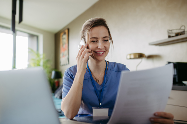 Nurse paying bills online, working on notebook. Doctor working from home, after workday, telemedicine consultation, phone calling. Work-life balance for healthcare worker.