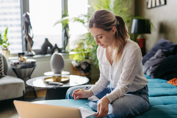 Nurse paying bills online, working on notebook. Doctor working from home, after workday, telemedicine consultation from living room. Work-life balance for healthcare worker.