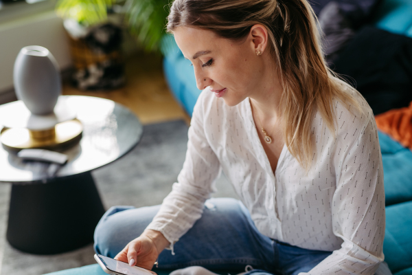 Female nurse, doctor enjoying free time at home after work. Portrait of beautiful woman with smartphone in hand.