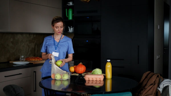 Female nurse, doctor returning home from work with groceries for family. Work-life balance of healthcare worker as parent and partner.