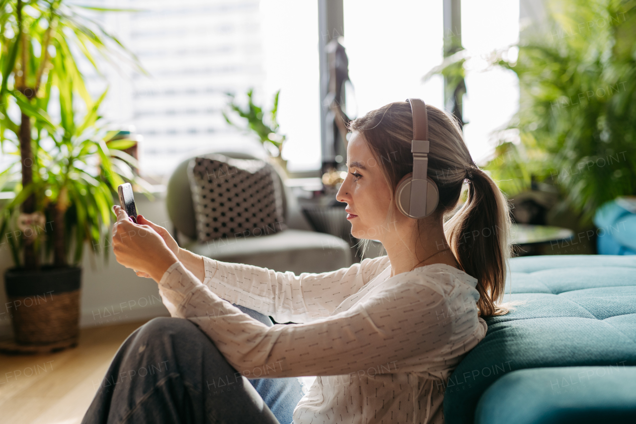 Female nurse or doctor enjoying free time at home after work, sitting in bedroom and listening meditation relaxing music. Work-life balance for a healthcare worker.