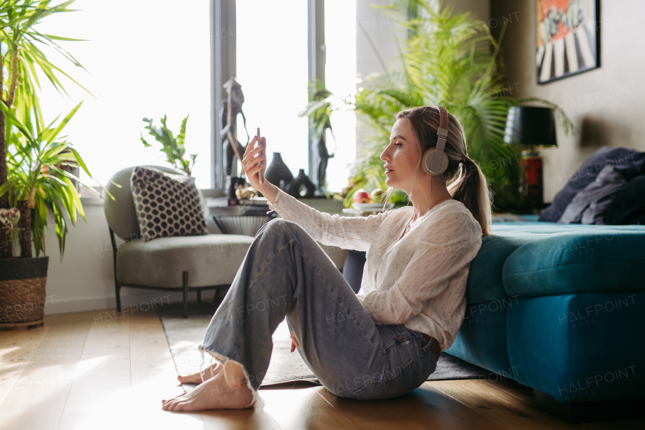 Female nurse or doctor enjoying free time at home after work, sitting in bedroom and listening meditation relaxing music. Work-life balance for a healthcare worker.