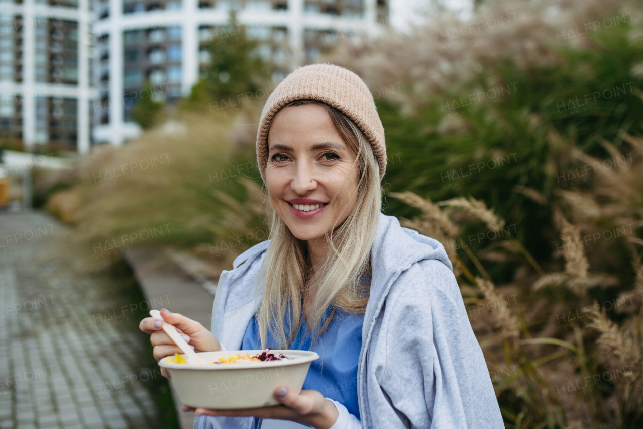 Nurse having healthy lunch or snack in front of hospital building, taking break from work. Importance of breaks in healthcare.