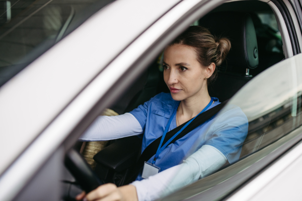 Female nurse sitting in car, going home from work. Female doctor driving car to work, on-call duty. Work-life balance of healthcare staff.