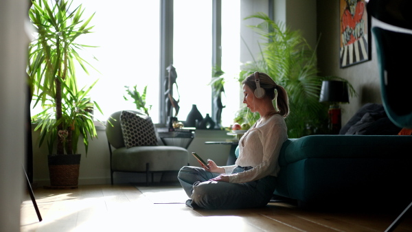 Female nurse or doctor enjoying free time at home after work, sitting in bedroom and listening meditation relaxing music. Work-life balance for a healthcare worker.