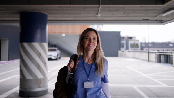 Female nurse, doctor walking across hospital parking lot, going home from work. Work-life balance of healthcare worker.