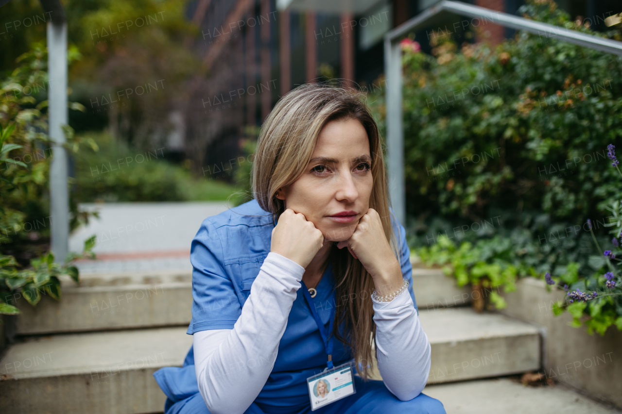 Young female doctor feeling overwhelmed at work, sitting on stairs. Healthcare workers having stressful job, feeling exhausted. Burnout syndrome for doctors and nurses.