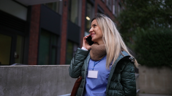 Female nurse or doctor going home from work, phone calling on smartphone. Work-life balance of healthcare worker as parent and partner.