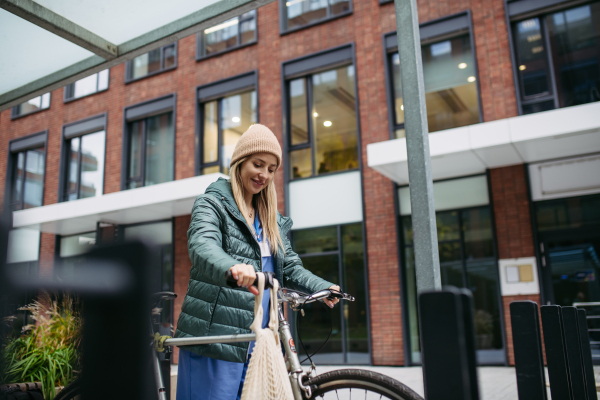 Beautiful nurse commuting through the city by bike. Doctor city leaving the hospital by bike after long workday. Grocery shopping.