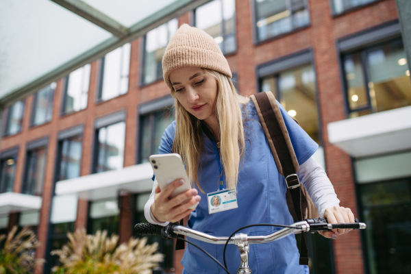 Beautiful nurse commuting through the city by bike. Doctor city commuter traveling from work by bike after long workday in clinic.