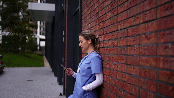 Young female doctor feeling overwhelmed at work, getting a puase outside. Healthcare workers having stressful job, feeling exhausted.