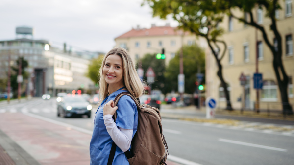 Nurse, doctor in uniform walking across city, going to work, hospital, clinic. Work-life balance of healthcare worker.