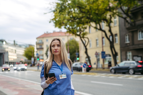 Nurse, doctor in uniform walking across city, going to work, hospital, clinic. Work-life balance of healthcare worker.