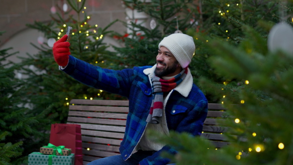 Happy smiling multiracial man with presents at Christmas market.