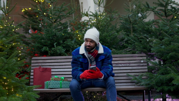 Happy smiling multiracial man with presents at Christmas market.