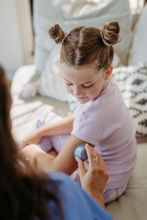 Nurse applying a continuous glucose monitor sensor to the arm of a diabetic girl. CGM device making life of school girl easier, helping manage his illness and focus on other activities.