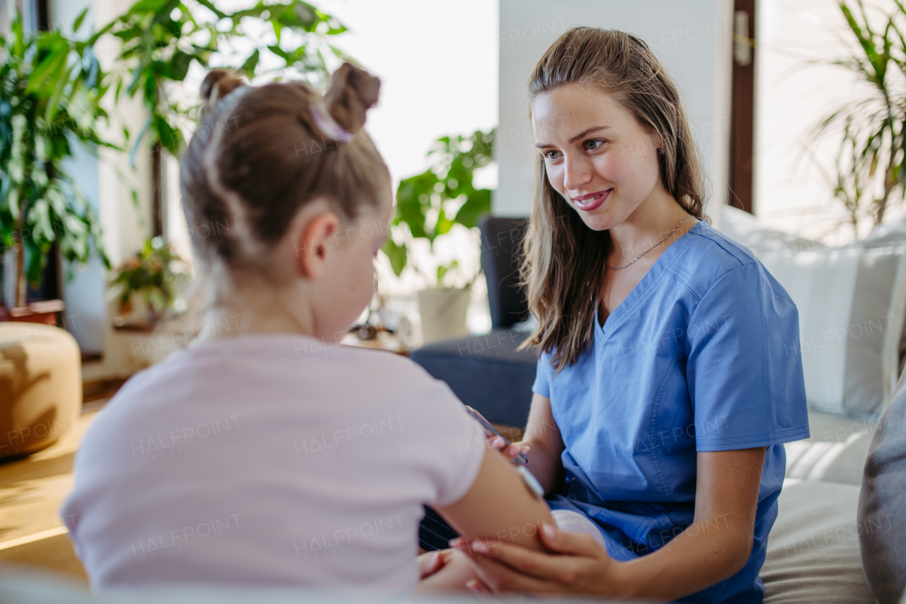 Nurse applying a continuous glucose monitor sensor to the arm of a diabetic girl. CGM device making life of school girl easier, helping manage his illness and focus on other activities.