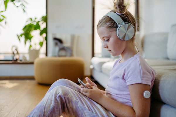 Diabetic girl watching social media content on smart phone.The CGM device makes the life of the schoolgirl. easier, helping manage his illness and focus on other activities.