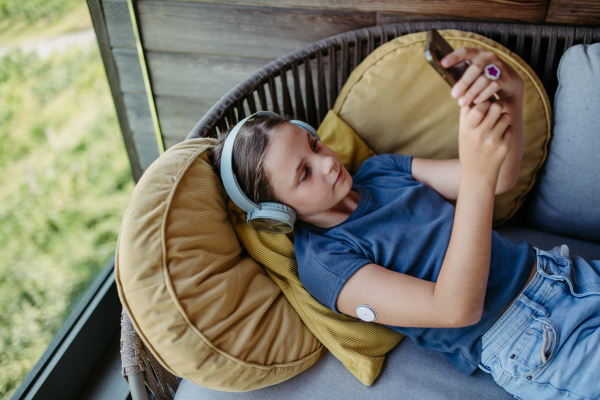 Diabetic girl watching social media content on smart phone.The CGM device makes the life of the schoolgirl. easier, helping manage his illness and focus on other activities.