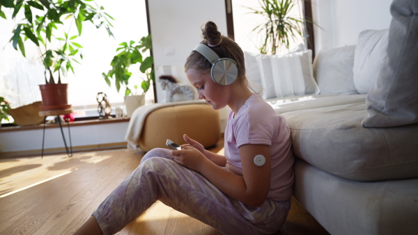 Diabetic girl watching social media content on smart phone.The CGM device makes the life of the schoolgirl. easier, helping manage his illness and focus on other activities.