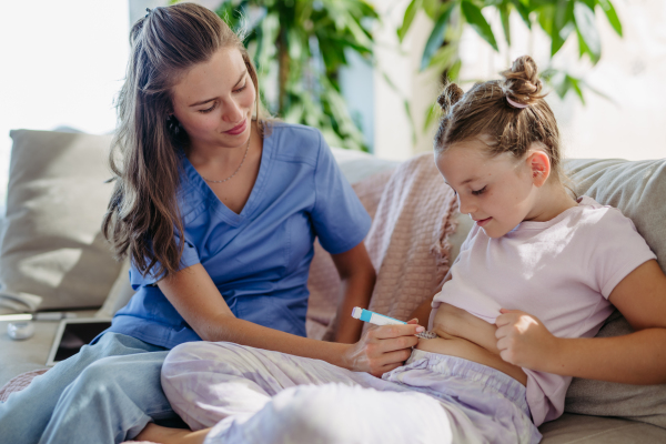 Nurse injecting insulin in diabetic girl belly. Close up of young girl with type 1 diabetes taking insuling with syringe needle.