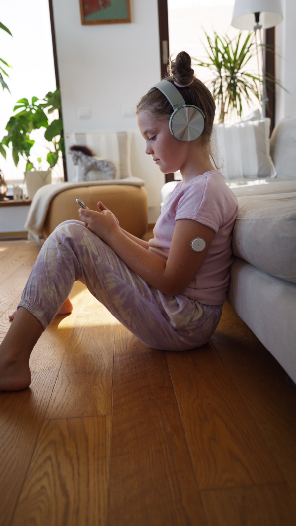 Diabetic girl watching social media content on smart phone.The CGM device makes the life of the schoolgirl. easier, helping manage his illness and focus on other activities.