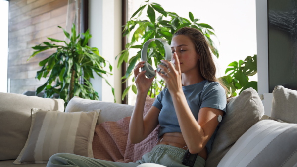 Diabetic woman with continuous glucose monitor sitting ondoors on sofa, watching social media content on smart phone.The CGM device makes the life of the schoolgirl. easier, helping manage his illness and focus on other activities.