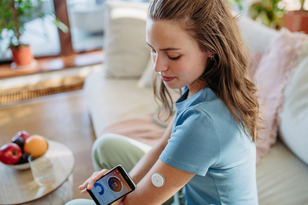 Woman with diabetes using continuous glucose monitor. Diabetic woman connecting CGM to a smartphone to monitor her blood sugar levels in real time.