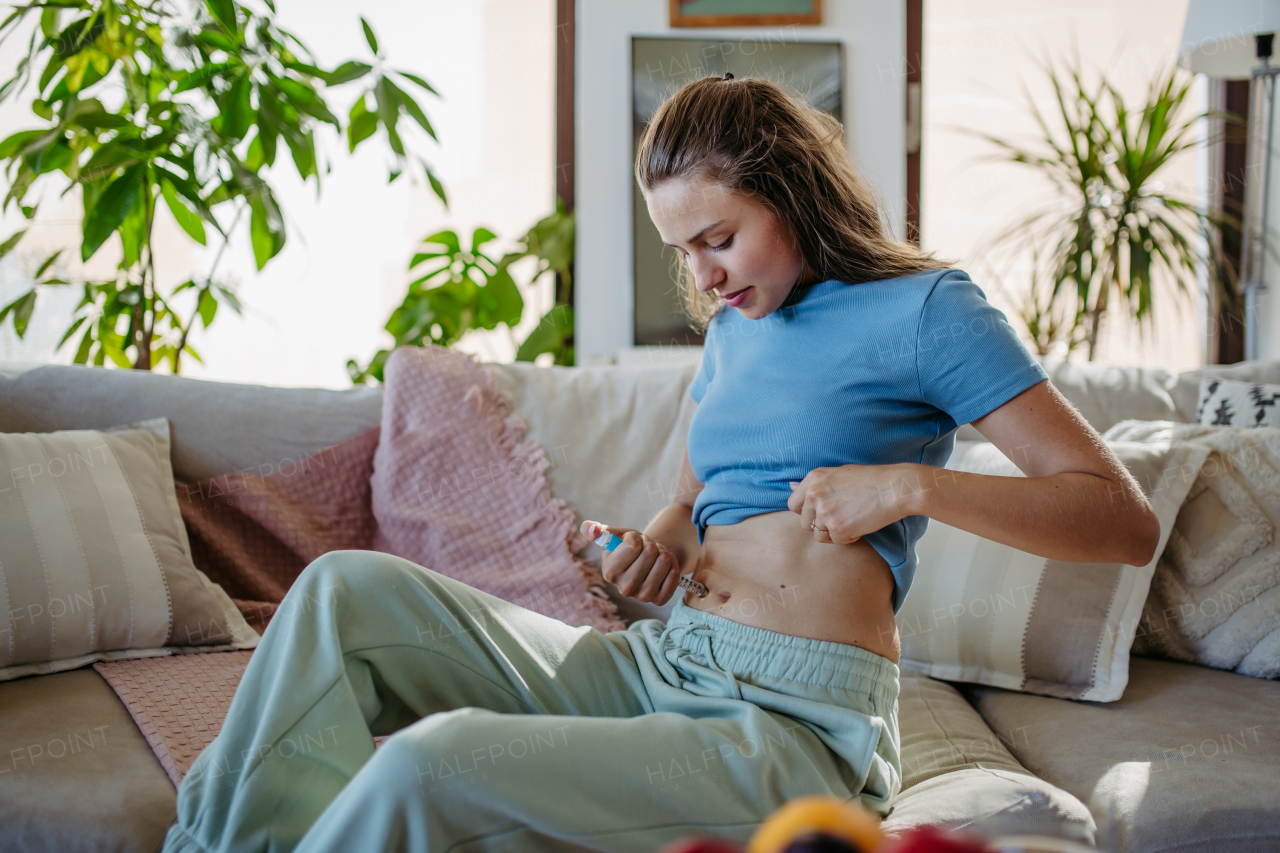 Young diabetic woman injecting insulin into her abdomen, belly.