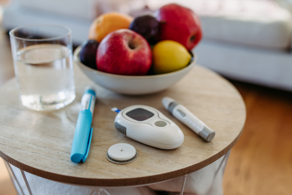 Close up of diabetes supplies and devices on the table. Continuous glucose monitor, insulin pen, blood glucose meter. Image with copy space.